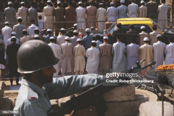 Sunni Muslims pray at a mosque with police security after they were attacked by Shia Muslims, Karachi, Pakistan, 1996.