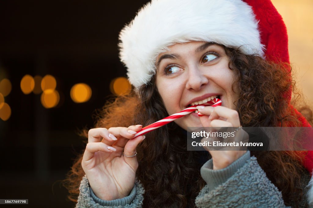 Young woman eating a Christmas candy cane