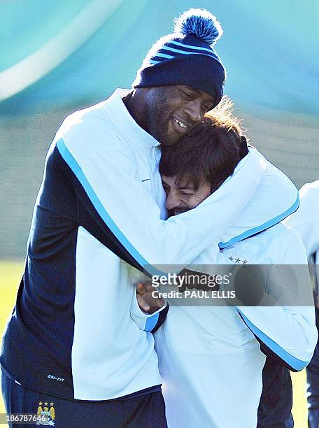 Manchester City's Ivorian midfielder Yaya Toure hugs Manchester City's Spanish midfielder David Silva as they take part in a training session in...