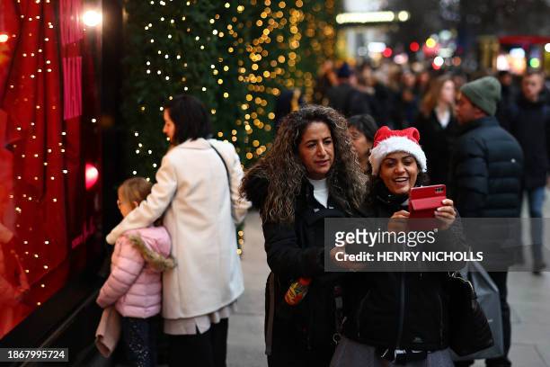 Shoppers take a picture on Oxford Street on the final weekday before Christmas in London on December 22, 2023. Britain's economy unexpectedly shrank...