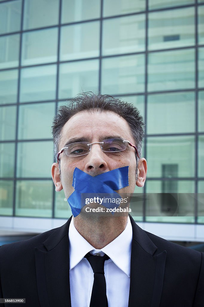 Businessman with Adhesive Tape Over Mouth