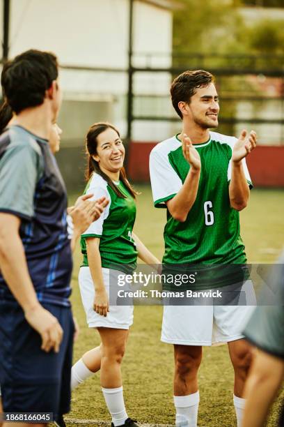 wide shot smiling soccer players applauding after game on rooftop field - championship day three stock pictures, royalty-free photos & images