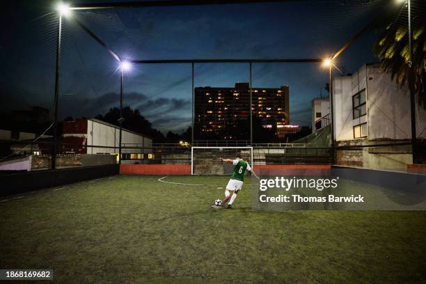 extreme wide shot soccer player taking penalty kick on rooftop field - strafstoß serie fußball und andere sportarten stock-fotos und bilder