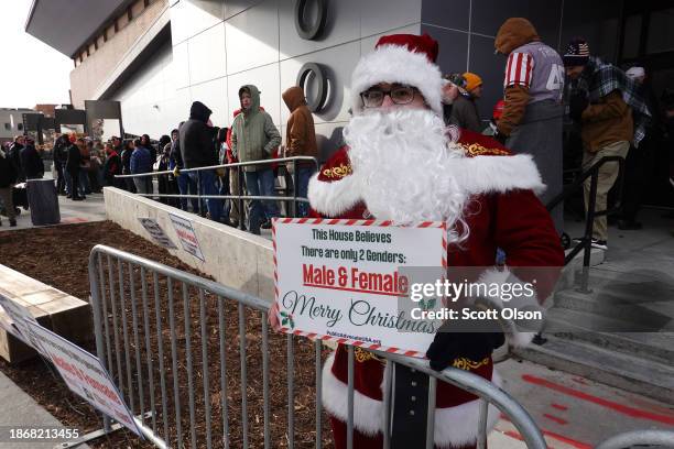 Santa Claus holds up a sign as guests wait in line to attend a campaign event hosted by Republican presidential candidate former President Donald...