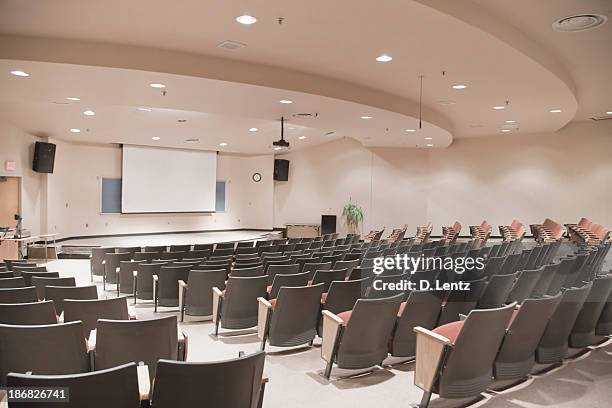 empty lecture hall with several rows of seats and a screen - classroom stock pictures, royalty-free photos & images