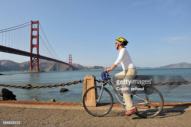 a photo of a woman cycling near the golden gate bridge - individual event stock pictures, royalty-free photos & images