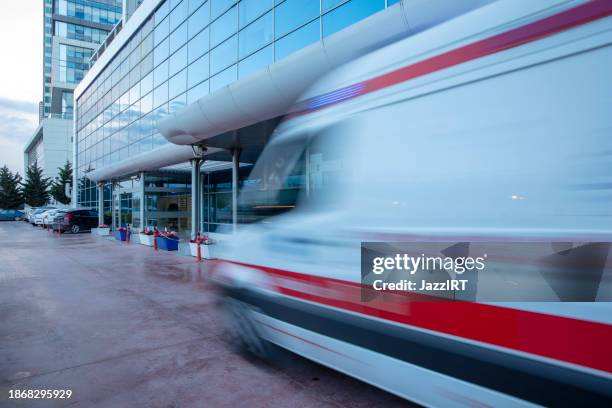 ambulance arriving at hospital. ambulance quickly arriving in front of the modern hospital. - motion sickness stock pictures, royalty-free photos & images