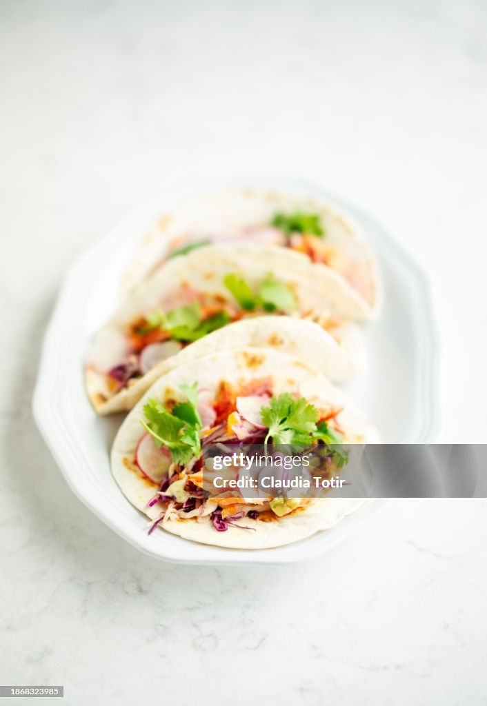 Fish (salmon) tacos on a plate on white background