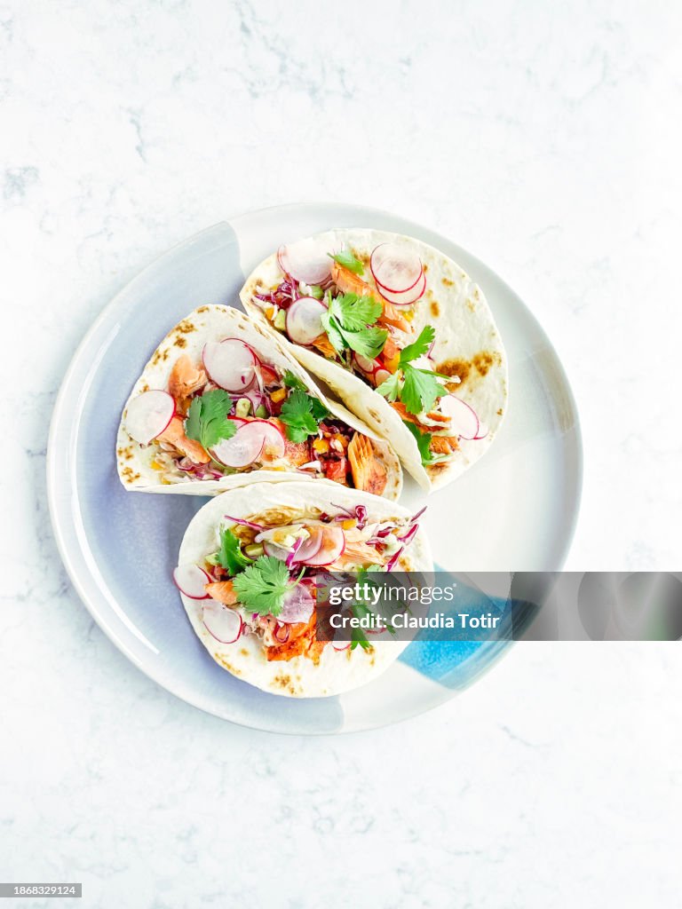 Fish (salmon) tacos on a plate on white background