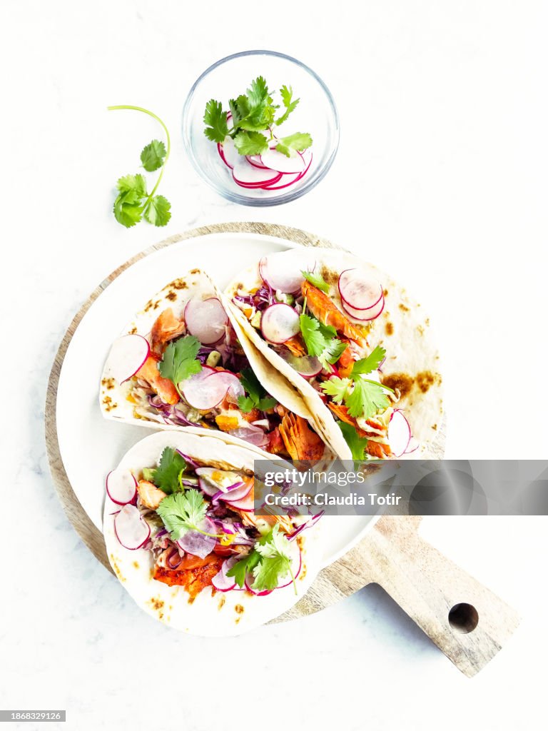 Fish (salmon) tacos on cutting board on white background