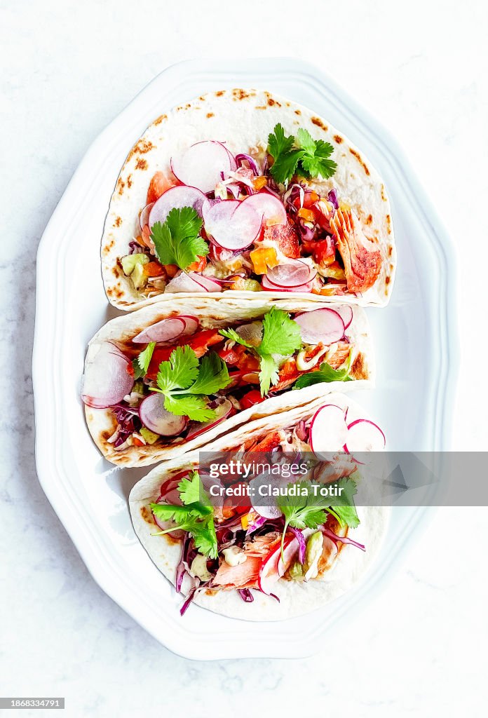 Fish (salmon) tacos on a plate on white background