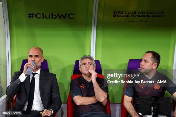 Pep Guardiola the head coach / manager of Manchester City takes his seat in the dugout alongside his assistant Juanma Lillo and technical assistant...