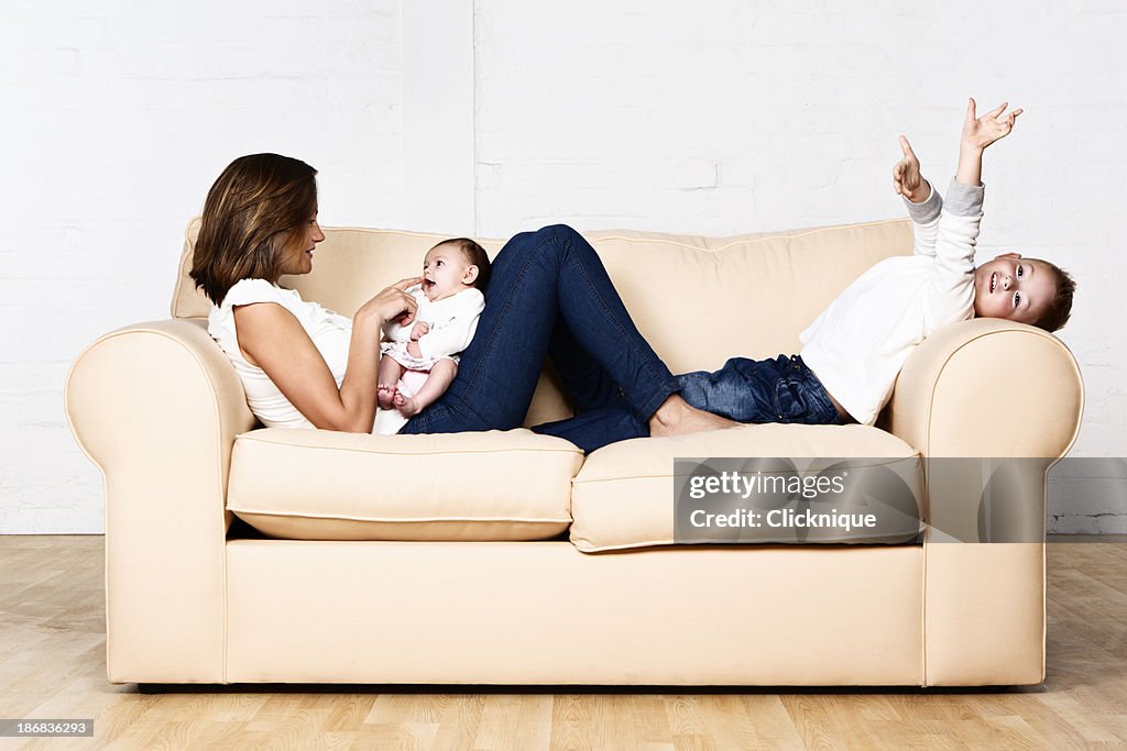 Family fun: mother son and baby daughter relaxing on sofa