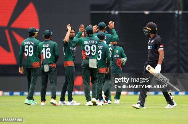 New Zealand's Rachin Ravindra walks from the field after being caught as Bangladesh celebrates during the third one-day international cricket match...