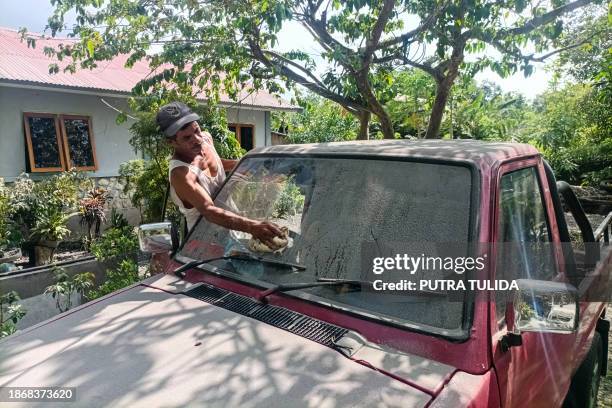 Man wipes volcanic ash off the windscreen of his car after Mount Lewotobi Laki-Laki erupted in Klatanlo, East Nusa Tenggara on December 23, 2023.