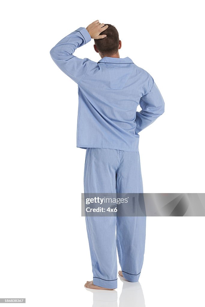 Rear view of a man in pajamas scratching head