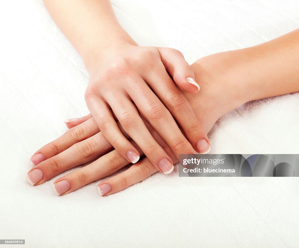 Close-up of a woman's hands crossed on a white background