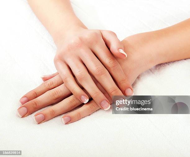 close-up of a woman's hands crossed on a white background - french manicure stock pictures, royalty-free photos & images