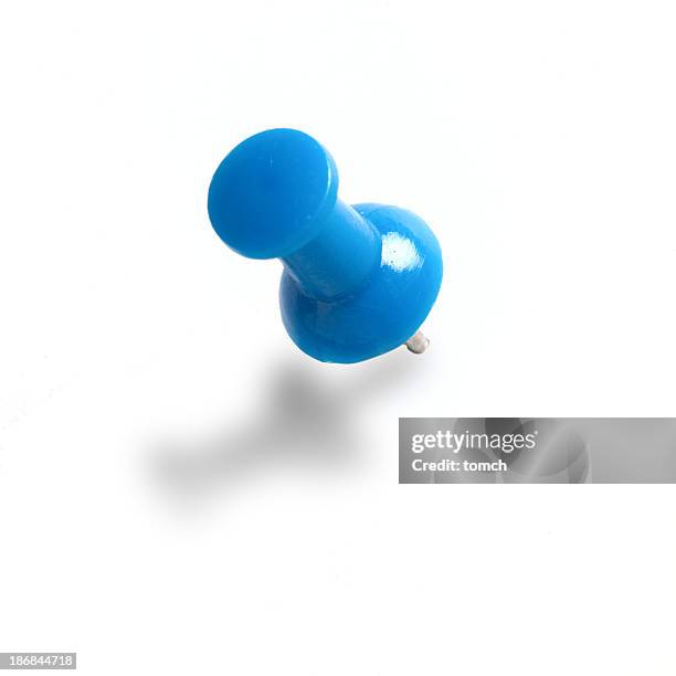 a blue push pin on a white wall - punaise stockfoto's en -beelden
