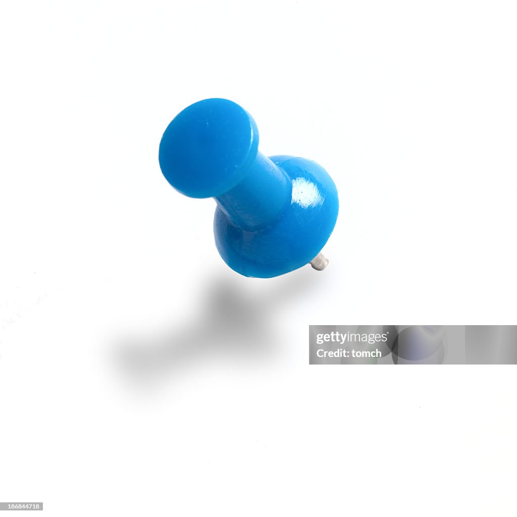 A blue push pin on a white wall