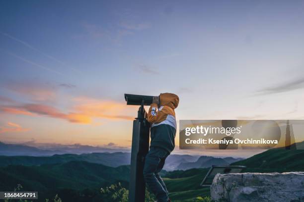 small boy looking through binoculars in nature. - telescopes stock pictures, royalty-free photos & images
