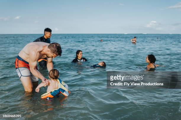 father holds baby son in ocean water - mother and child in water at beach stock pictures, royalty-free photos & images