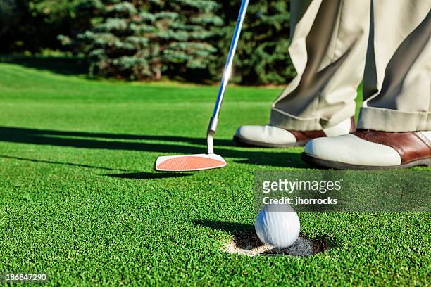 golfer sinking a short putt - golf short iron stock pictures, royalty-free photos & images