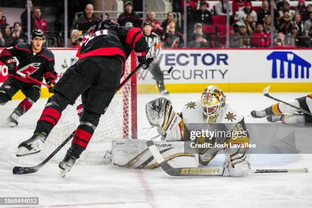 Logan Thompson of the Vegas Golden Knights makes a save against Sebastian Aho of the Carolina Hurricanes during the first period at PNC Arena on...