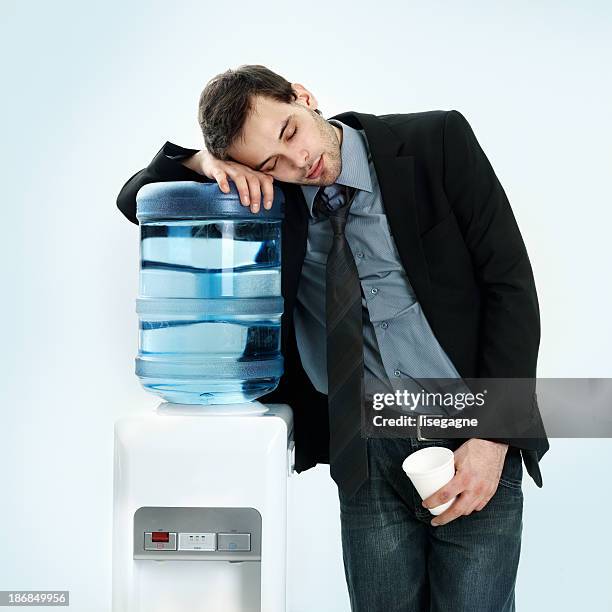 businessman resting on water cooler - water cooler white background stock pictures, royalty-free photos & images