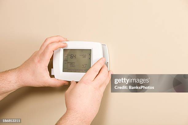 electrician installing new programmable thermostat - thermostat stock pictures, royalty-free photos & images