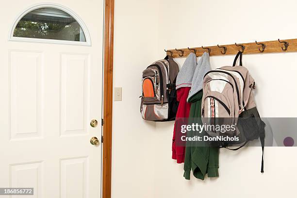 backpacks and jackets by backdoor - coat hanging stock pictures, royalty-free photos & images