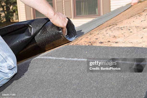 roofer unrolling weather guard tar paper - rolling stock pictures, royalty-free photos & images