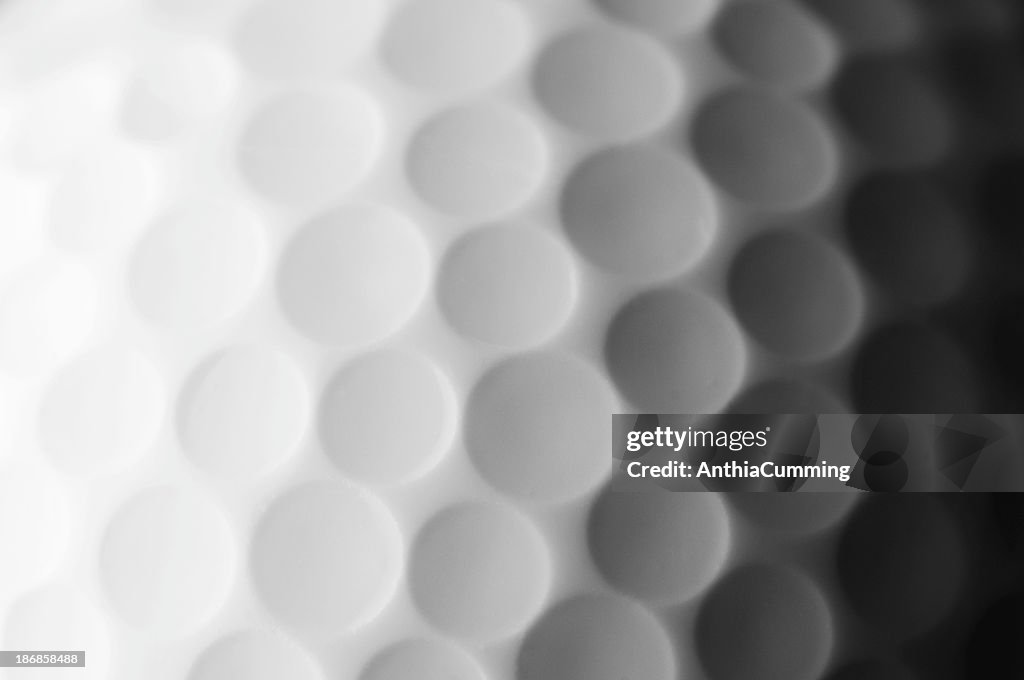 A close up shot of a golf ball, white and fade to dark gray