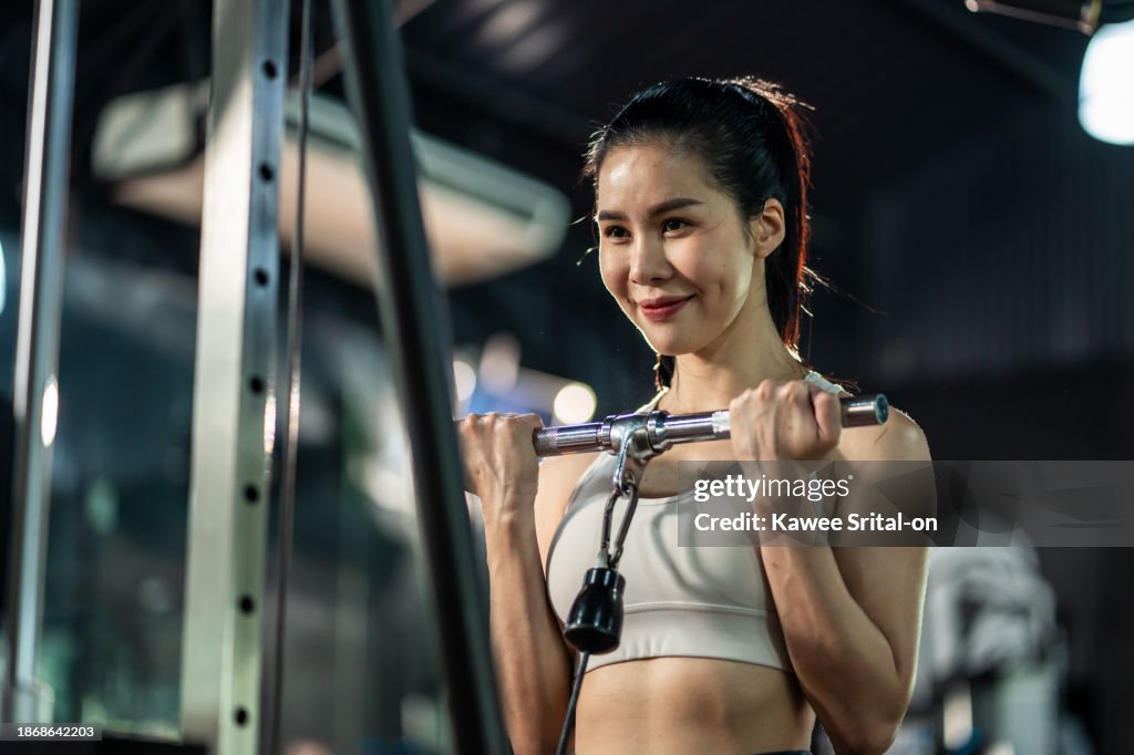 Asian young sportswoman trainer exercise to build muscle in stadium. Attractive bodybuilder athlete girl in sportswear workout by lifting weight dumbbell for health care lifestyle at fitness gym club.