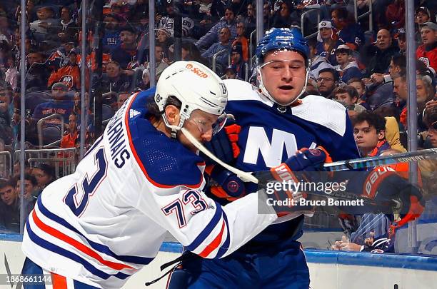 Vincent Desharnais of the Edmonton Oilers checks Julien Gauthier of the New York Islanders during the second period at UBS Arena on December 19, 2023...