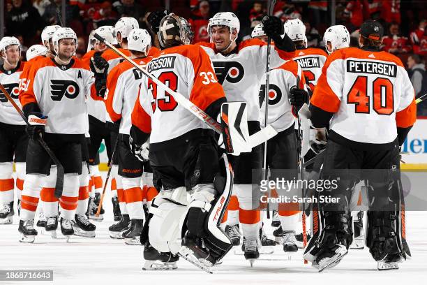 Garnet Hathaway celebrates with Samuel Ersson of the Philadelphia Flyers after their team's win during overtime against the New Jersey Devils at...