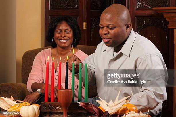 kwanzaa couple horizontal red candles lit - kwanzaa celebration stock pictures, royalty-free photos & images
