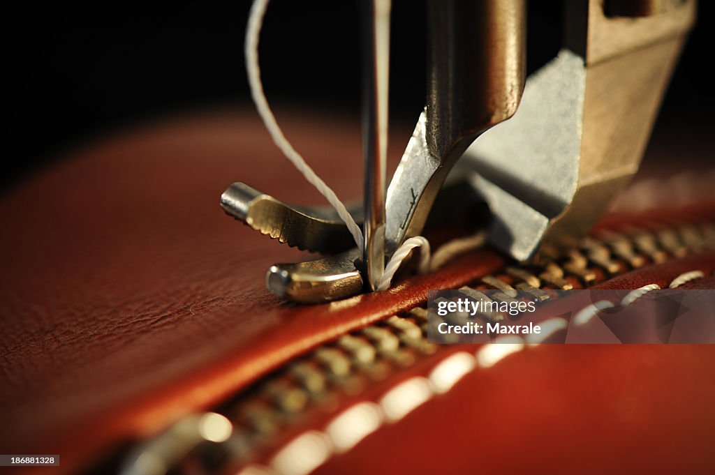 Close-up of a sewing machine with needle on red leather