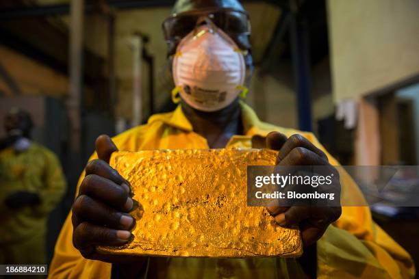 Mine worker displays a large ingot of gold after cleaning and hammering it during the refining process at the production plant for the Loulo-Gounkoto...