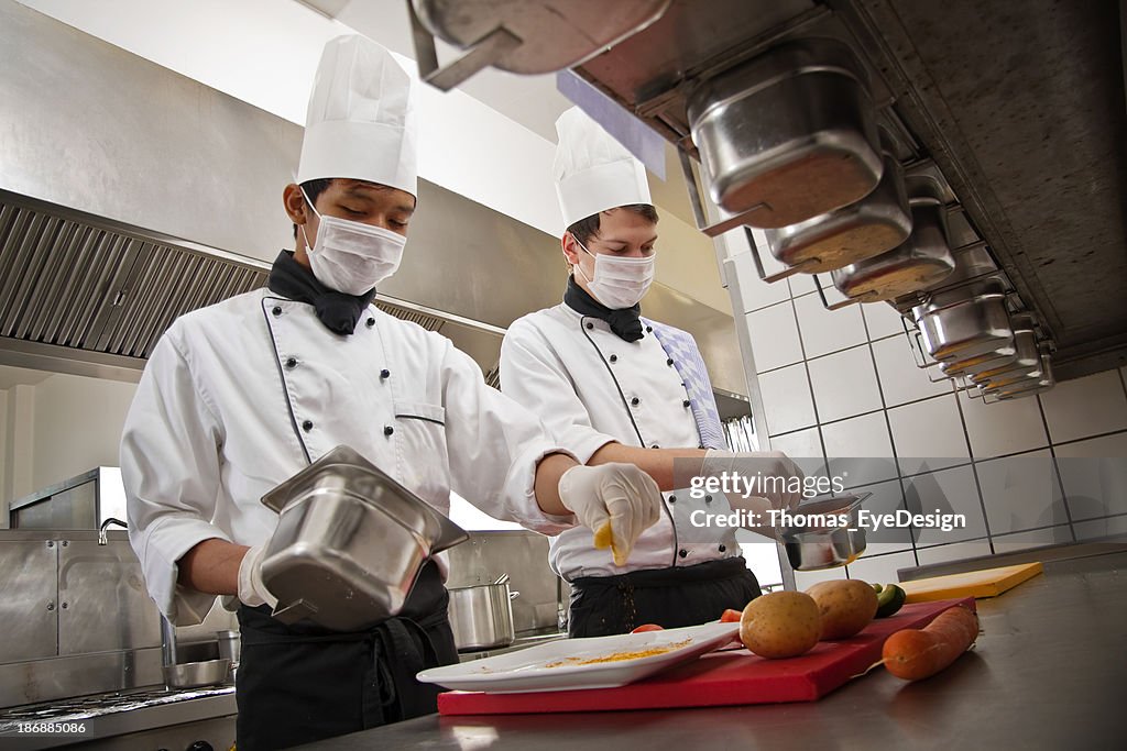 Chef and trainee work in a hotel kitchen, preparing a meal