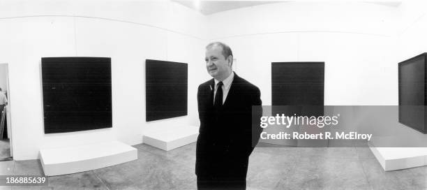 The painter Ad Reinhardt stands in a gallery during an exhibiton of his abstract paintings at the Museum of Modern Art, possibly during the...