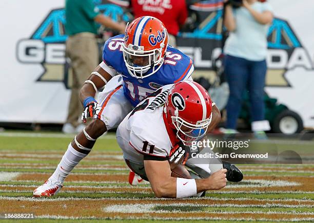 Aaron Murray of the Georgia Bulldogs is sacked for a safety by Loucheiz Purifoy of the Florida Gators during the game at EverBank Field on November...