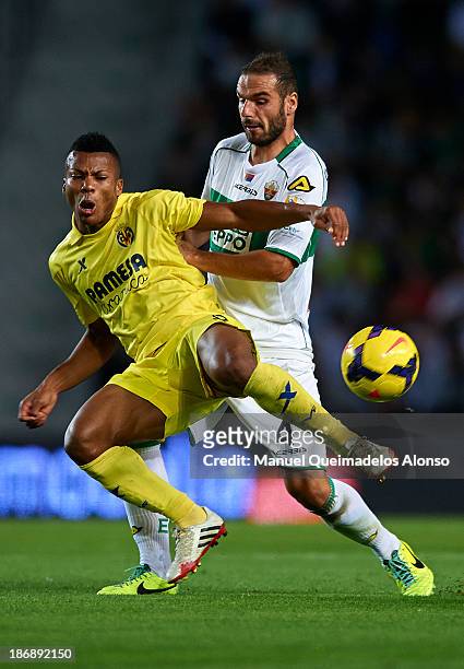 David Lomban of Elche competes for the ball with Ikechukwu Uche of Villarreal during the La Liga match between Elche CF and Villarreal CF at Estadio...
