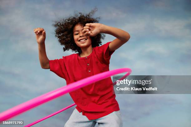happy boy spinning pink plastic hoop with arms raised - gymnastikreifen stock-fotos und bilder