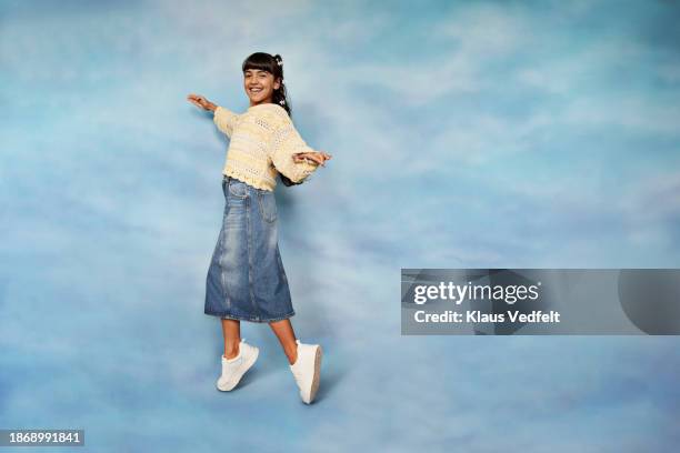full length portrait of smiling girl tiptoeing - girls denim skirts stock pictures, royalty-free photos & images