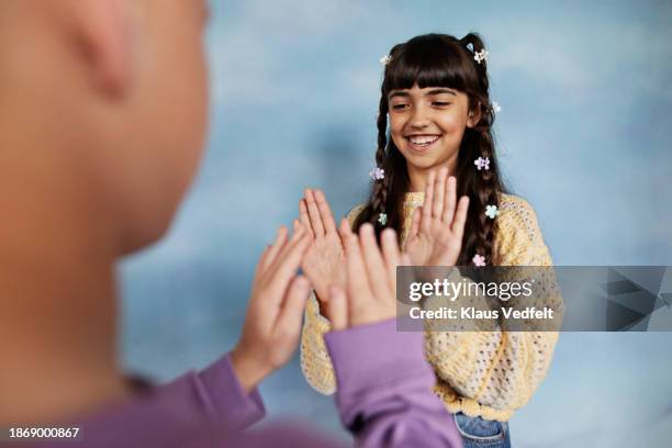 girl giving high-five to boy while playing hand game - girls hands behind back stock pictures, royalty-free photos & images