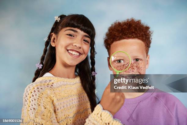 smiling girl holding magnifying glass over friend's face - iranian people stock pictures, royalty-free photos & images