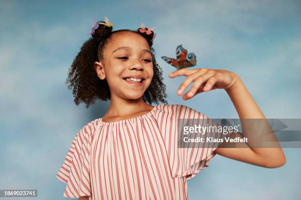 happy girl in striped top looking at butterfly on finger - budding tween stock pictures, royalty-free photos & images