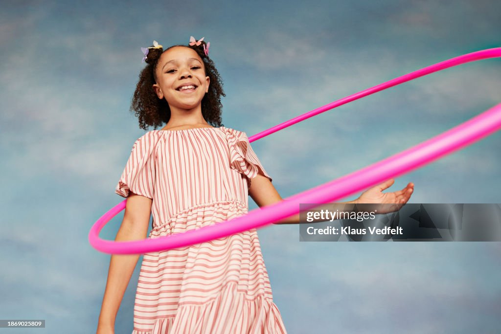 Smiling girl in striped dress with pink plastic hoop