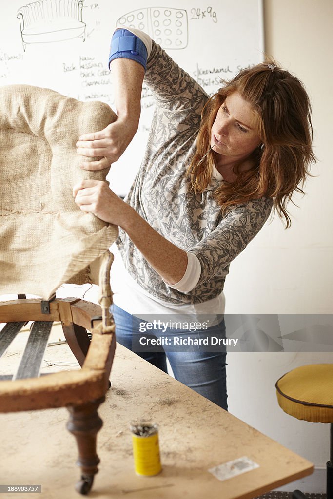 Upholsterer fitting hessian to old chair